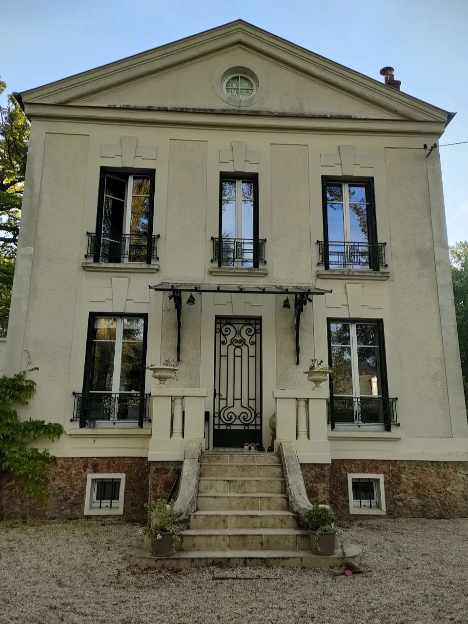 Façade crème et terne d’une maison bourgeoise à fronton et oculus, avant l’intervention d’Artisans L.L